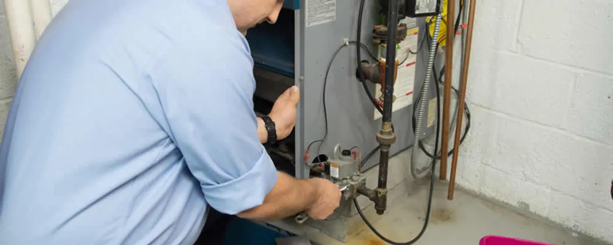Furnace repair technician inspecting and servicing a home heating system in Kansas City, KS