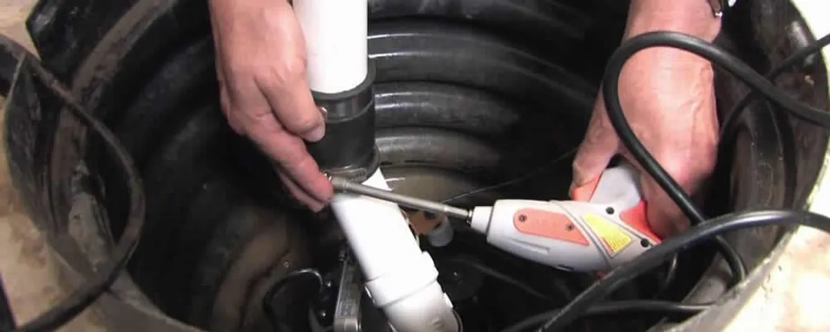 Sump pump installation technician connecting PVC discharge piping in Kansas City, KS